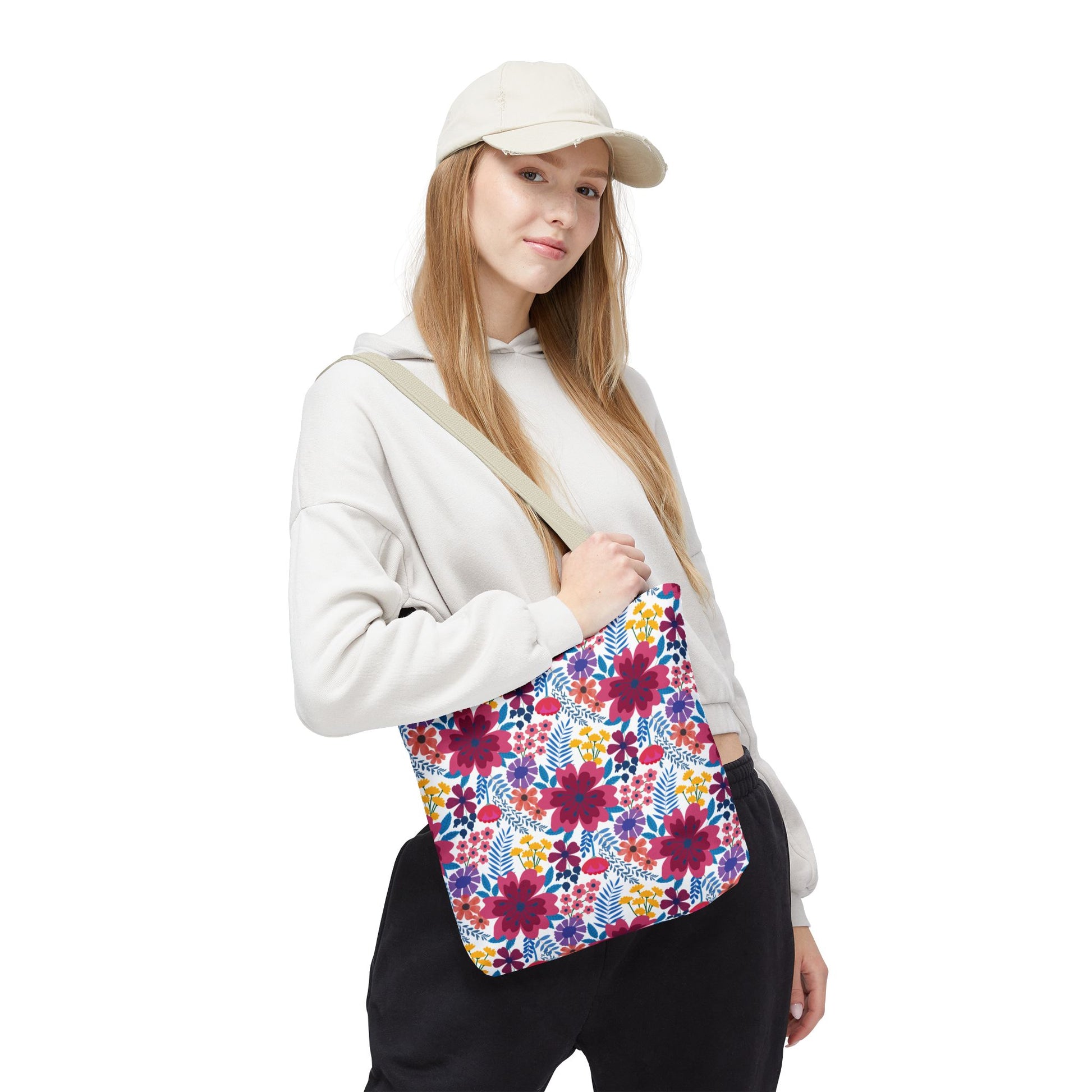 Model showcasing a Floral Tote Bag featuring vibrant magenta blooms and colorful floral accents, perfect for summer outings. The bag is paired with a light hoodie and cap, embodying FireBrook Essentials' joyful style.
