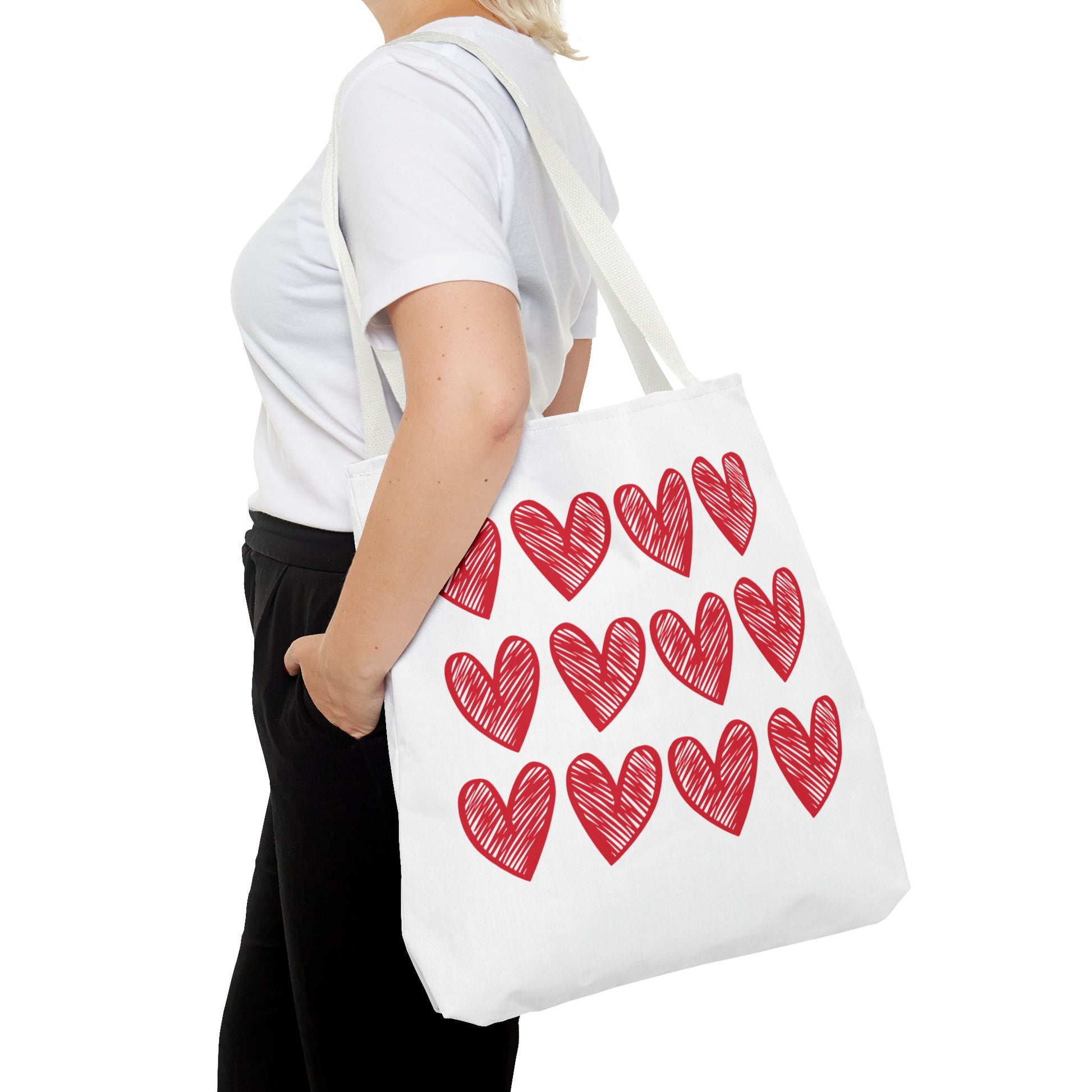 Hearts Tote Bag: A charming white tote adorned with red hearts, ideal for adding a playful touch to any outfit. Features durable polyester material and reinforced handles, embodying FireBrook Designs' uplifting and joyful style.