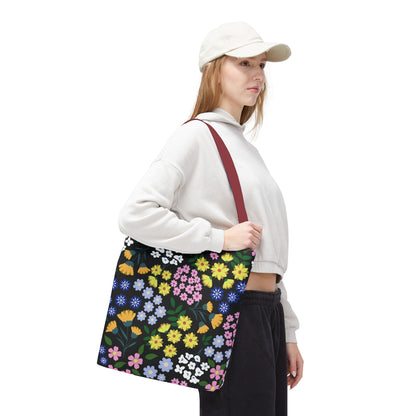 The Starry Night Blooms Tote Bag features a vibrant multicolored floral pattern, contrasting burgundy handles, and is worn over a shoulder, embodying FireBrook Essentials' cheerful, practical style.