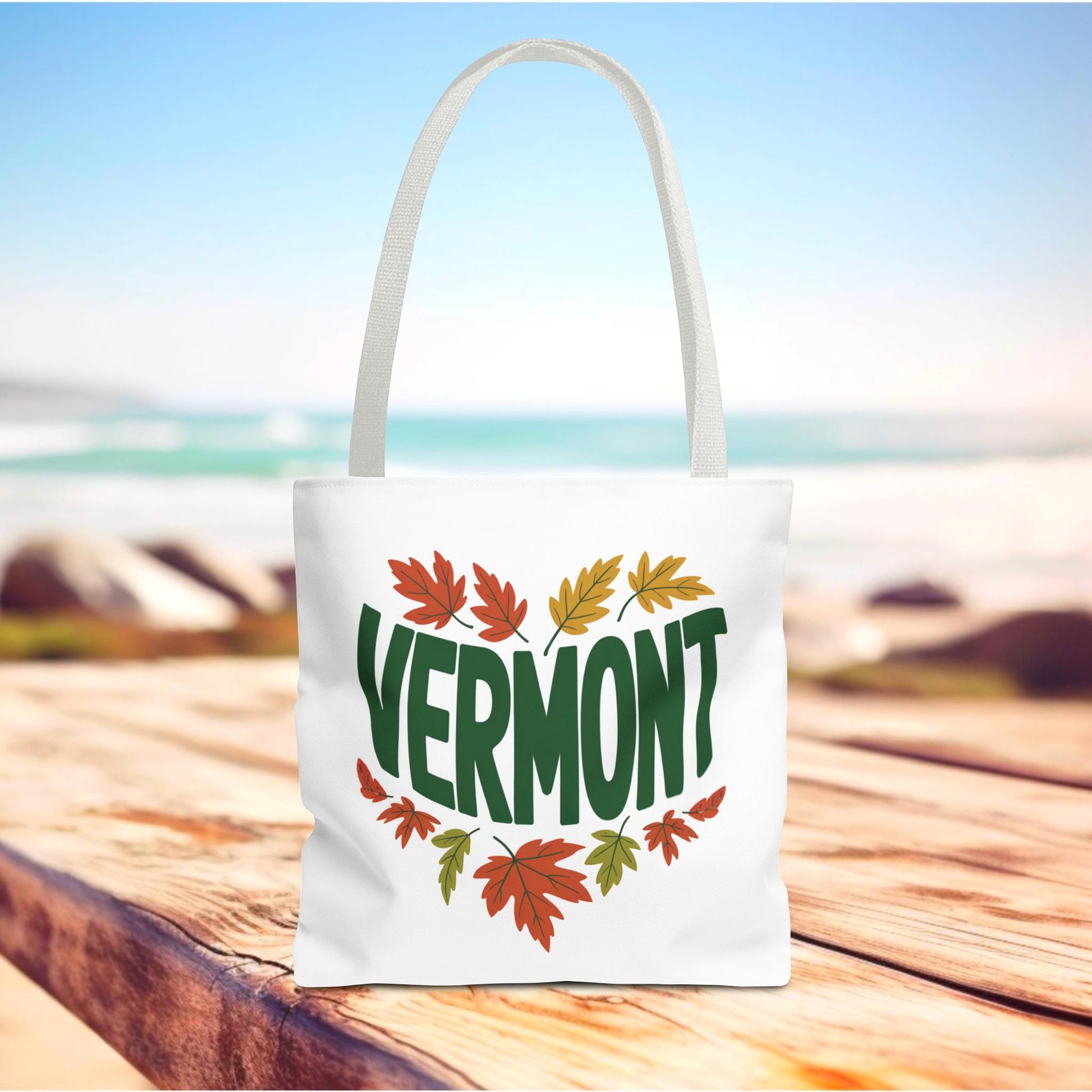 The Vermont Tote Bag showcases a stylish design with a white base adorned with green and orange leaves, emphasizing FireBrook Essentials' blend of durability and uplifting style for everyday use.