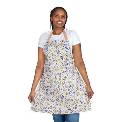 Woman models FireBrook Designs' Floral Apron, featuring a white base with blue and golden-yellow leaf prints. The apron offers full coverage, tie-back closure, and a soft, stain-free polyester canvas.