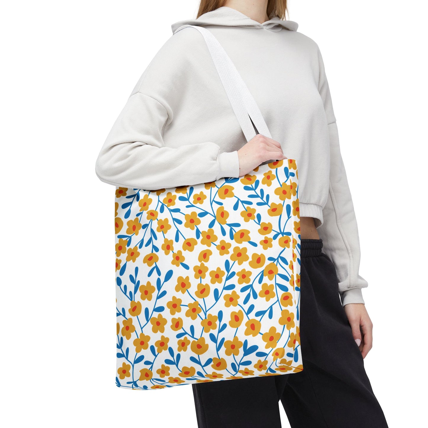 A person carries the Buttercup Cream Tote Bag, featuring a cheerful pattern of yellow-orange flowers and blue branches, perfect for stylish summer outings. The tote exemplifies FireBrook Essentials' uplifting design ethos.