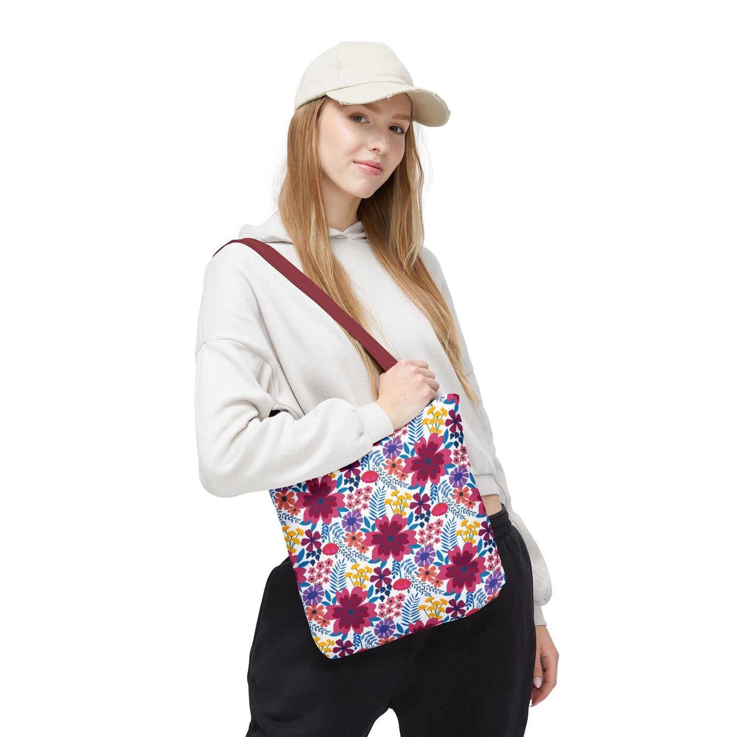 A young woman models the Violet Daisy Carnival Tote Bag, featuring vibrant floral patterns on a white background, complemented by a burgundy strap, ideal for adding a cheerful touch to summer outings.