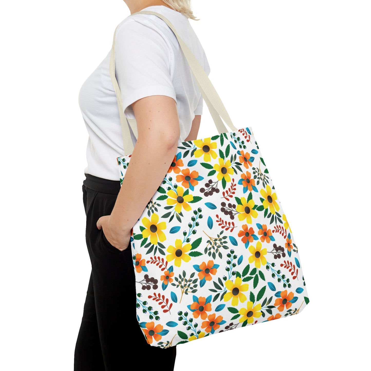 Sunny Meadow Mix Tote Bag featuring vibrant yellow and orange floral patterns with green and blue accents, carried over the shoulder by a person in a white T-shirt and black pants.