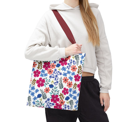 Floral Tote Bag featuring a vibrant pink, red, and blue blossom pattern with leafy accents on a white background, carried by a casually dressed person, showcasing its spacious design and burgundy strap.