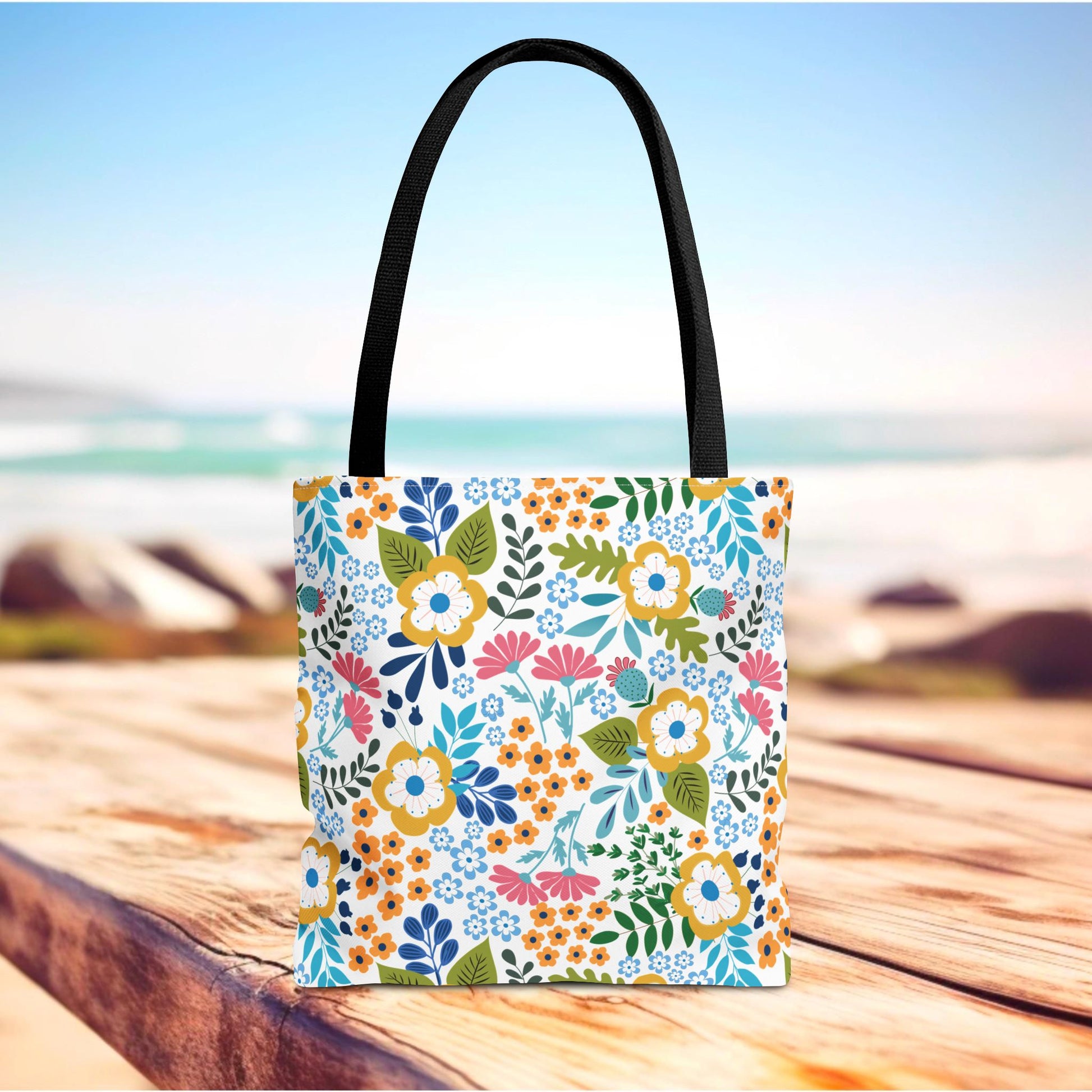 Floral Tote Bag on a wooden surface with a vibrant floral pattern, featuring durable black straps. Ideal for adding a cheerful touch to summer outings, embodying FireBrook Designs' uplifting style.