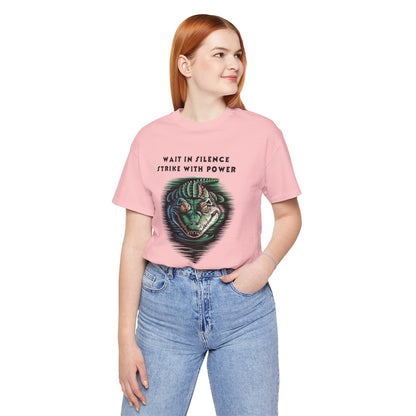 Crocodile: Walk in Silence, Strike with Purpose Bella+Canvas Unisex T-Shirt featuring a woman in a pink shirt and jeans, posing with a detailed crocodile design, reflecting bold, unique style.