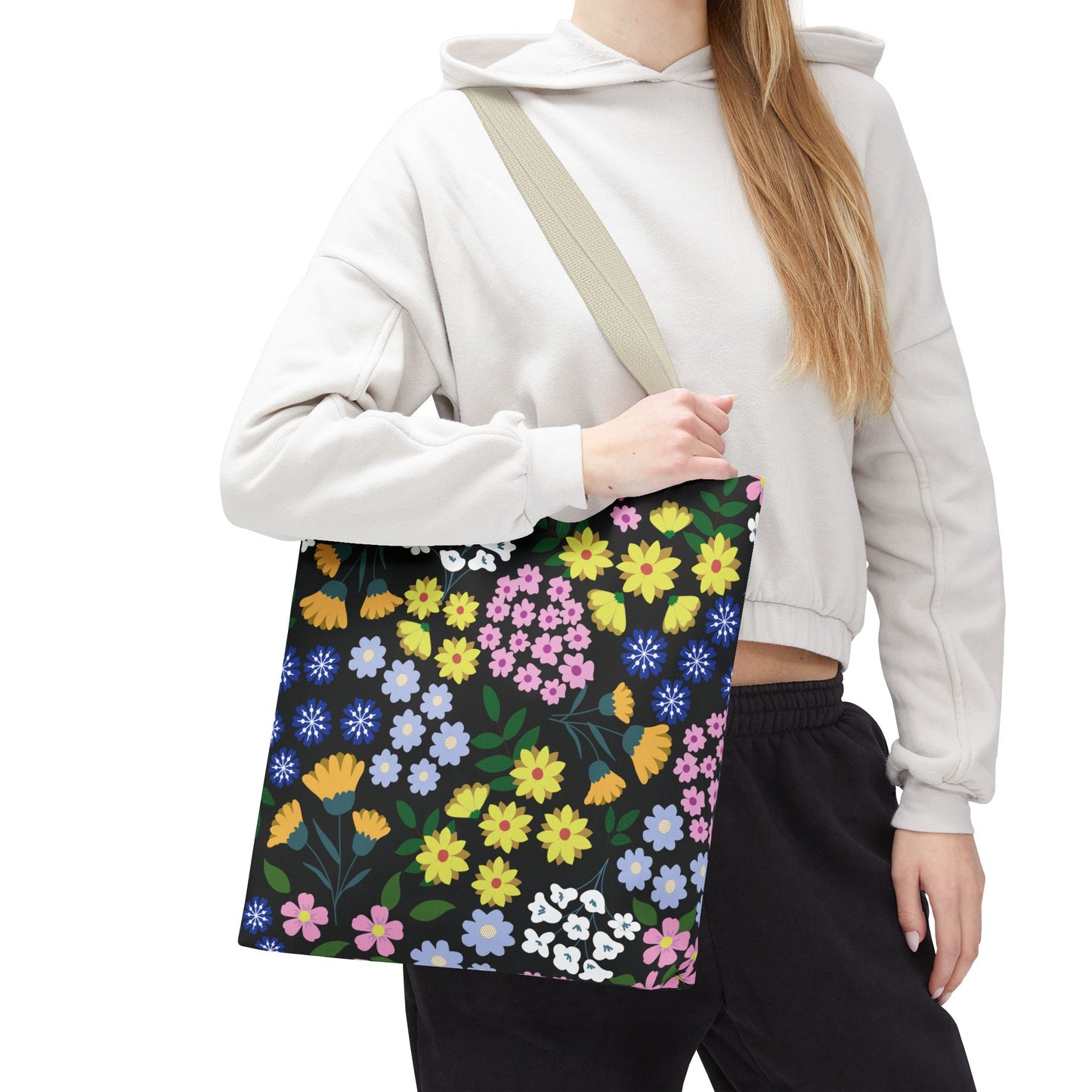Person wearing light-grey hoodie holds the Starry Night Blooms Tote Bag, featuring a vibrant floral pattern. Ideal for brightening summer activities, this durable polyester bag combines style and functionality, reflecting FireBrook Essentials' uplifting designs.