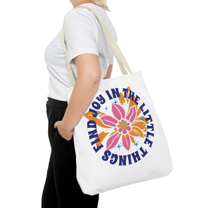 Woman holding the Find Joy in Little Things tote bag featuring a colorful flower design, ideal for spreading positivity and carrying essentials.