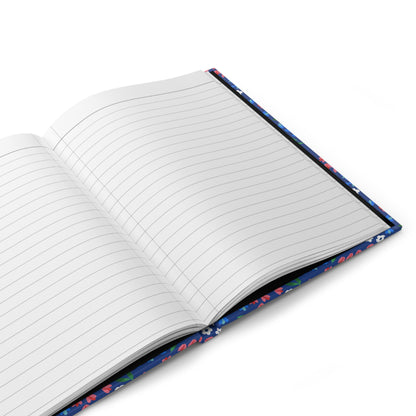 HARDCOVER JOURNAL, MATTE, RULED, 5X7, SEWN BIND, CLEAN-TEAR PAGES – WILDFLOWER SKY lies open, showcasing its lined pages on a white surface, with a glimpse of the vibrant floral cover edges.