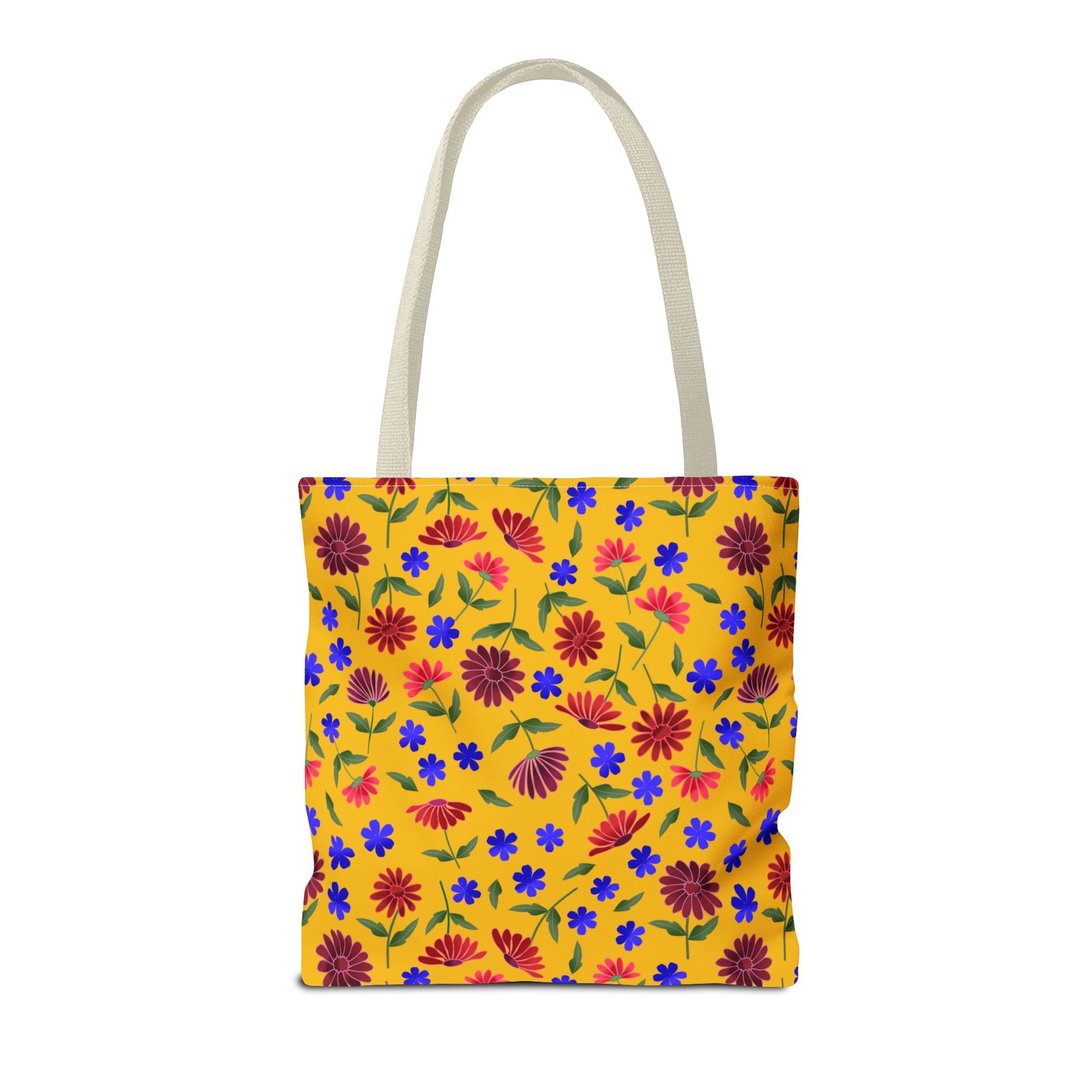 Golden Wildflower Tote Bag features a bright yellow canvas with vibrant red and pink daisies, scattered blue flowers, and green leaves. Black straps provide durability, perfect for stylish errands and daily use.