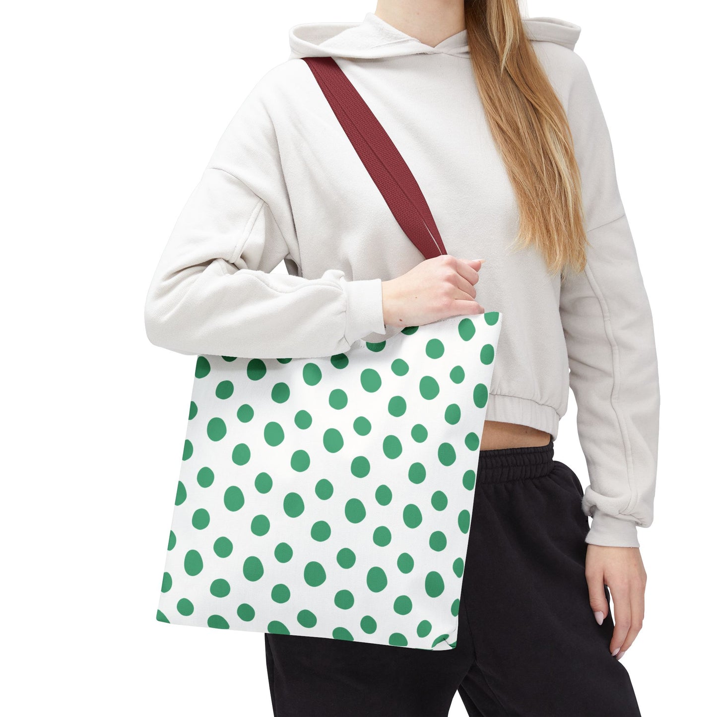 The Green Polka Dots Tote Bag held by a woman features a playful design with durable polyester, reinforced handles, and boxed corners, embodying FireBrook Essentials' commitment to stylish, joyful living.