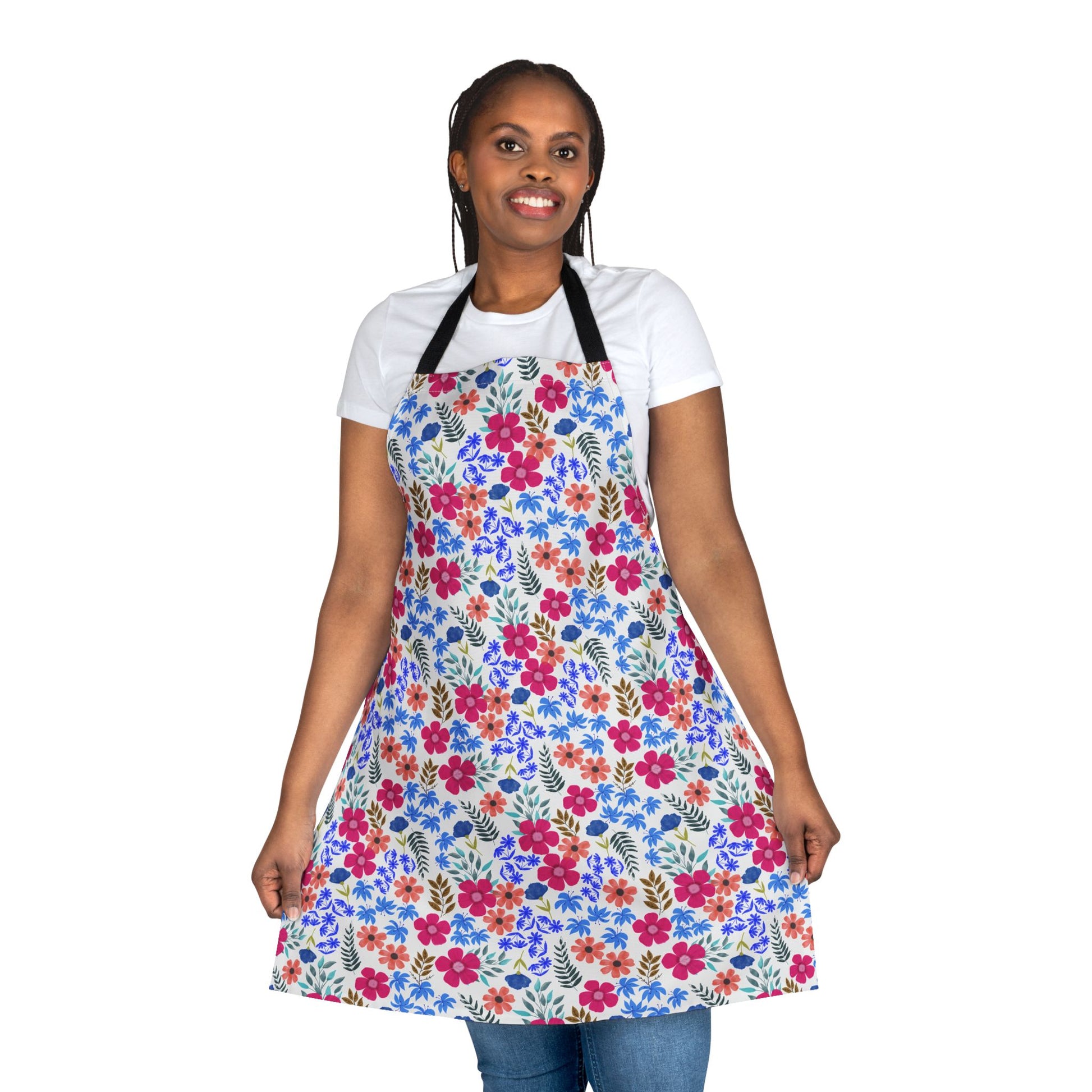 Woman wears Apron Floral Design, featuring vibrant pink, red, and blue blossoms with green foliage on a knee-length apron. Ideal for various activities with its comfortable polyester canvas and tie-back closure.