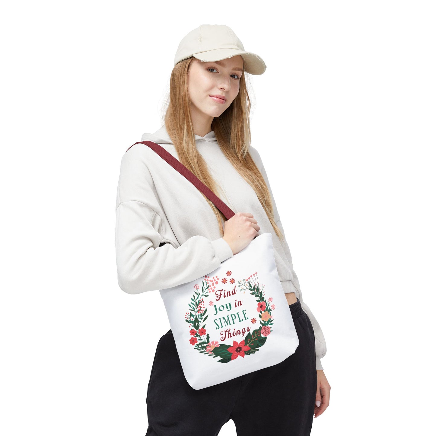 Woman in a white sweatshirt holds the 'Find Joy in Simple Things' tote bag with a watercolor floral design, highlighting its blend of style and functionality.