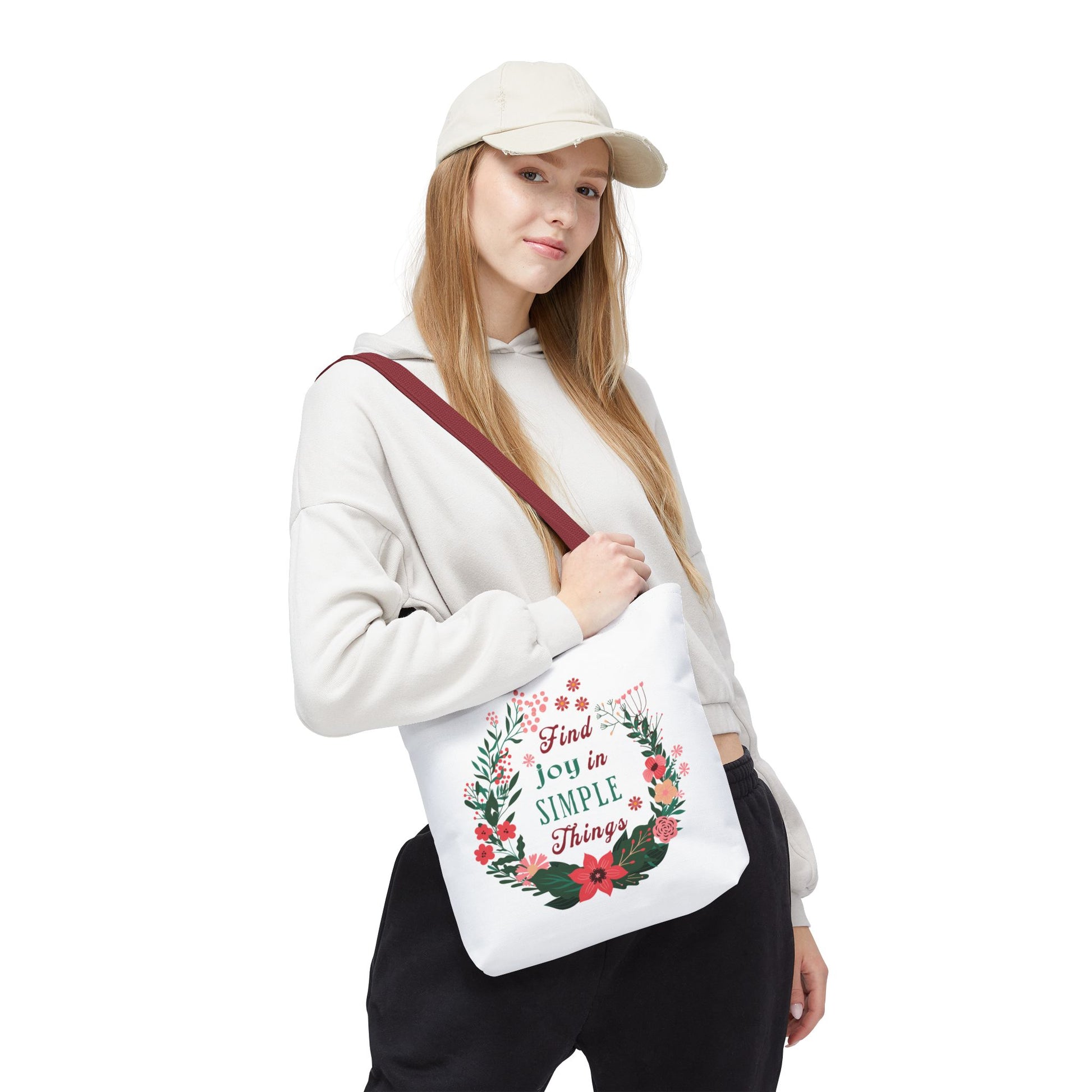 Woman in a white sweatshirt holds the 'Find Joy in Simple Things' tote bag with a watercolor floral design, highlighting its blend of style and functionality.