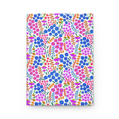 HARDCOVER JOURNAL, MATTE, RULED, 5X7, SEWN BIND, CLEAN-TEAR PAGES – WILDFLOWER PARADE features a vibrant floral design with clusters of blue, pink, and magenta flowers, embodying FireBrook Designs' uplifting style.