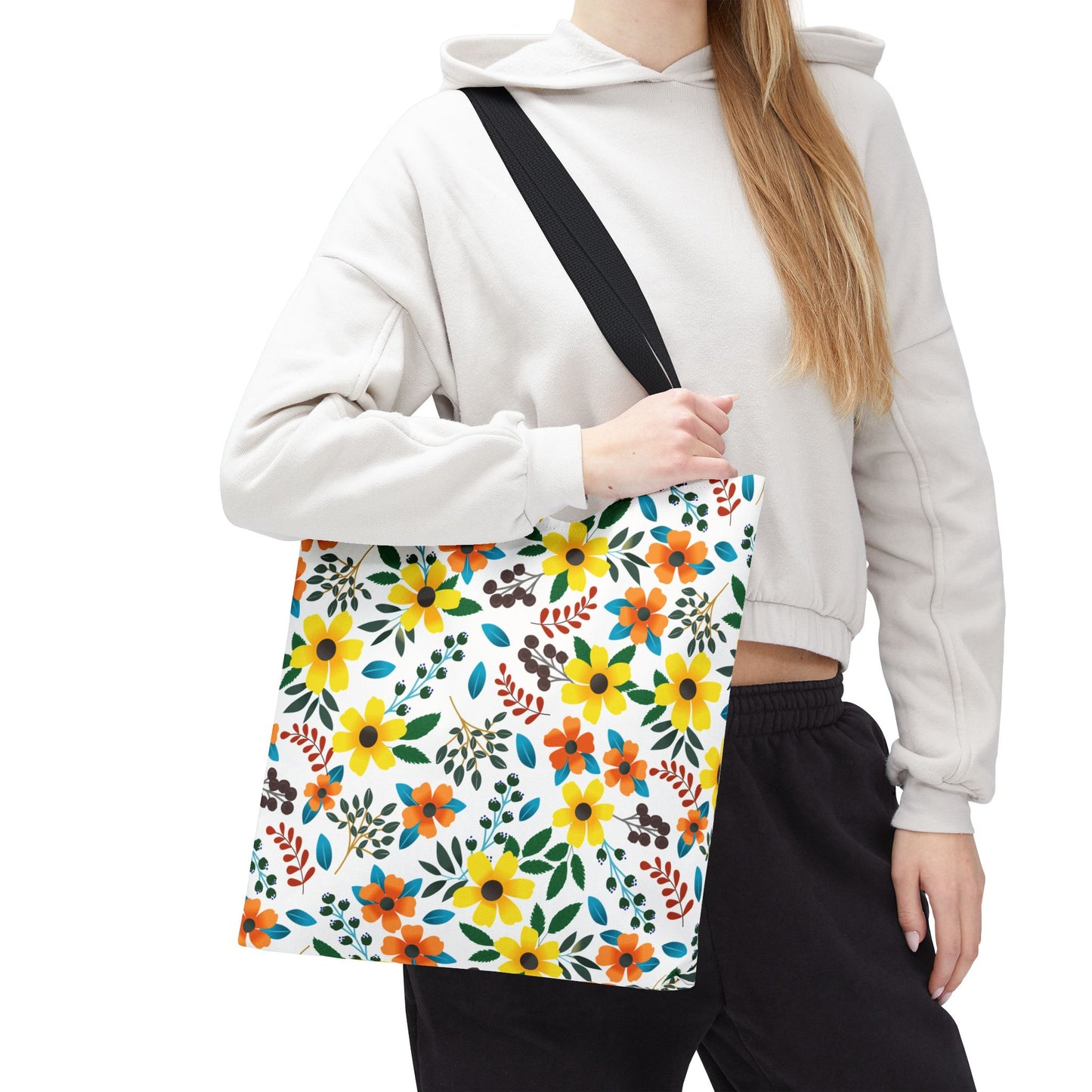 The Sunny Meadow Mix Tote Bag, featuring vibrant yellow and orange floral patterns, is slung diagonally over a shoulder, offering a cheerful accessory for summer outings, perfectly embodying FireBrook Designs' joyful aesthetic.