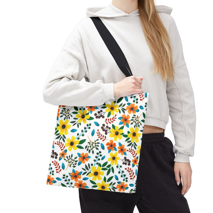 The Sunny Meadow Mix Tote Bag, featuring vibrant yellow and orange floral patterns, is slung diagonally over a shoulder, offering a cheerful accessory for summer outings, perfectly embodying FireBrook Designs' joyful aesthetic.