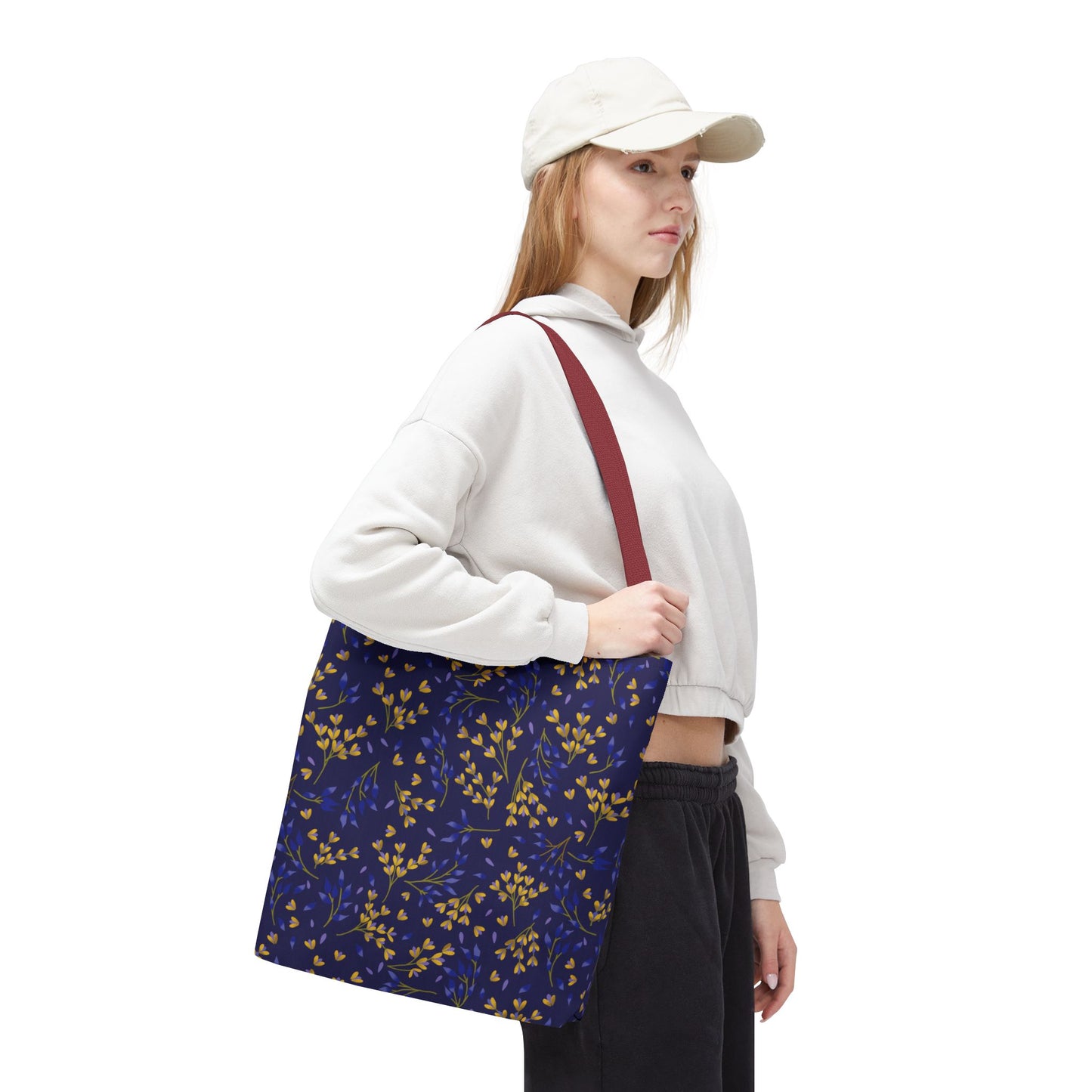 Floral Tote Bag featuring a vibrant yellow and blue leafy pattern on a navy background, carried by a person with a red strap, ideal for summer outings and joyful, stylish living.
