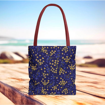 Floral Tote Bag with navy-blue base, adorned with mustard-yellow and periwinkle floral pattern, featuring brick-red straps, set on a sunlit wooden deck, ideal for joyful summer outings.