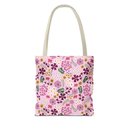Floral Tote Bag showcasing a vibrant floral pattern with purples, pinks, and yellows on a pink canvas, featuring natural beige straps. Ideal for daily essentials, combining style and durability.
