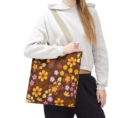 Floral Tote Bag with autumnal-toned stylized flowers on a dark brown background, carried by a person wearing a light hoodie and dark pants, perfect for brightening up summer outings.