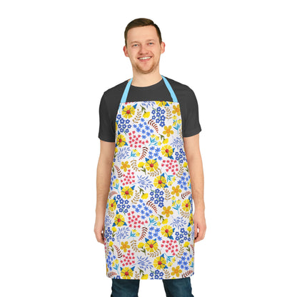 Young man wearing the Apron Floral Design by FireBrook Designs, showcasing a vibrant floral pattern with light blue straps, ideal for stylish cooking or crafting. Made from soft, stain-free polyester canvas.