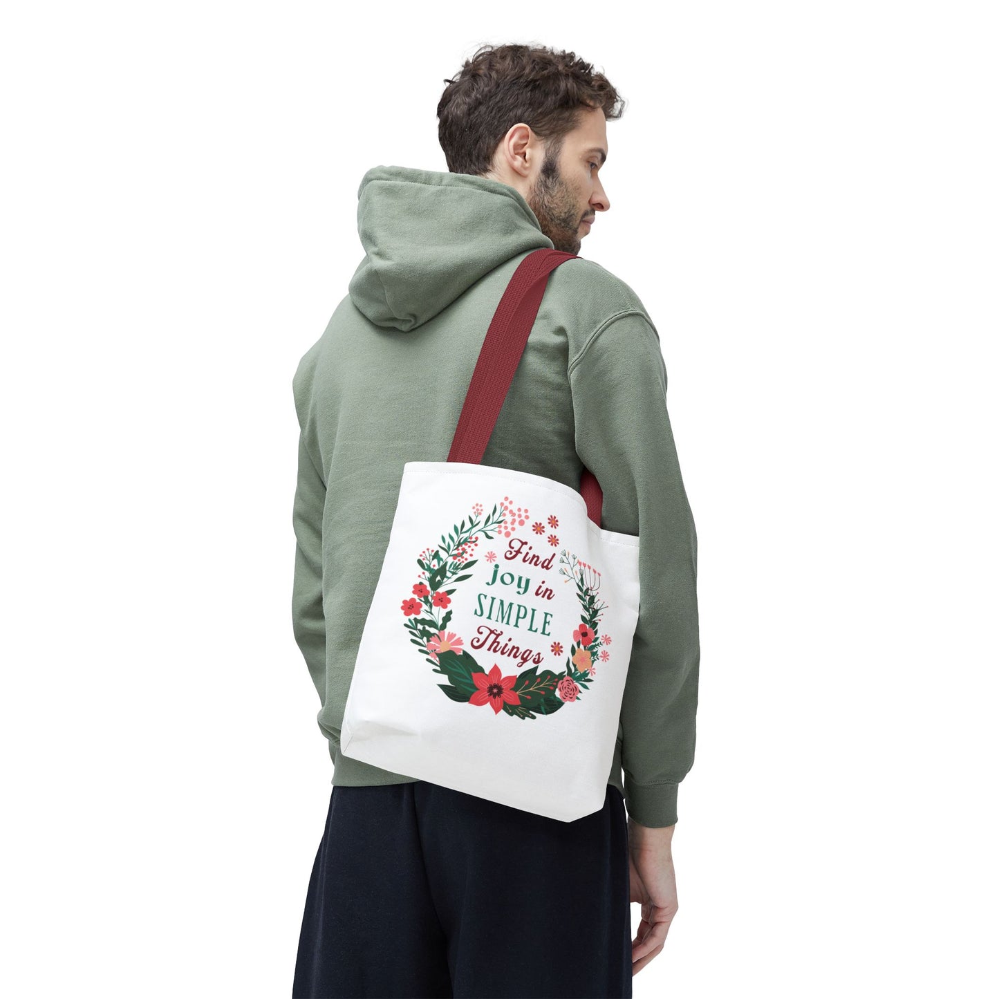 Man in green sweatshirt carrying 'Find Joy in Simple Things' tote bag with floral design, ideal for versatile, stylish use.