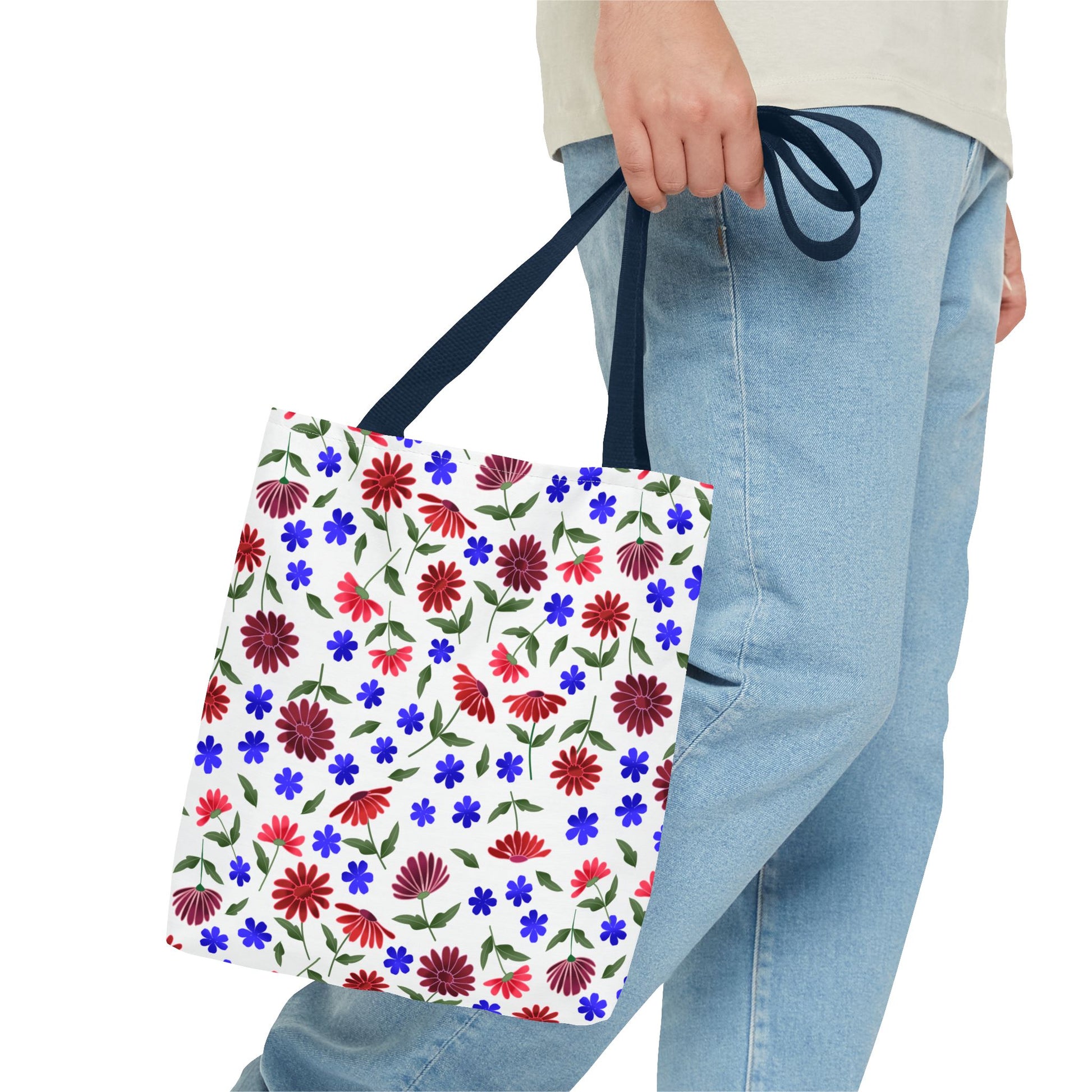 Floral Pattern Tote Bag — Red & Blue Wildflower All-Over Print held by a person in light-blue jeans, showcasing vibrant scattered flowers and navy handles, embodying FireBrook Designs' cheerful, practical style.