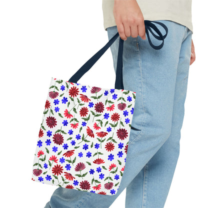 Floral Pattern Tote Bag — Red & Blue Wildflower All-Over Print held by a person in light-blue jeans, showcasing vibrant scattered flowers and navy handles, embodying FireBrook Designs' cheerful, practical style.