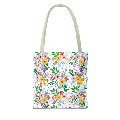 Floral Tote Bag featuring a vibrant pattern of yellow, pink, orange, and purple blossoms with green leaves on a white background. Ideal for summer, embodying FireBrook Designs' cheerful and uplifting style.