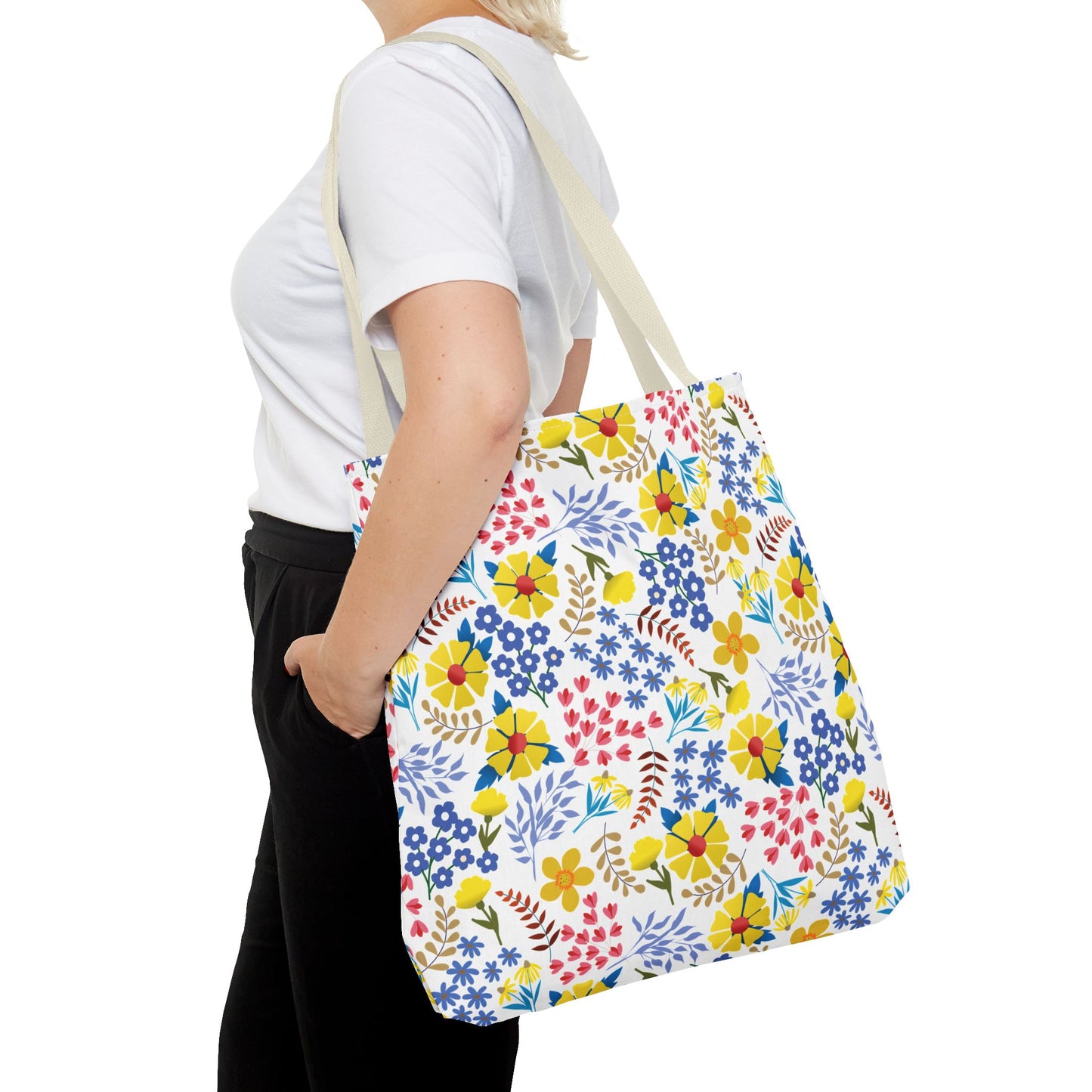 A person carries a Floral Tote Bag, featuring vibrant blossoms and green leaves. This FireBrook Designs accessory blends style and joy, perfect for summer outings and embodying cheerful, original design.