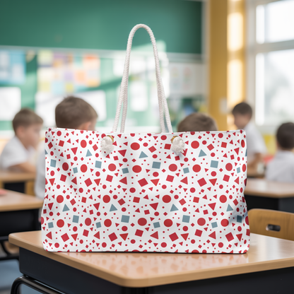 Geometric Pattern Weekender Bag – Red & Light Blue Modern Travel Tote on a desk. This spacious tote features rope handles and a T-bottom design, ideal for stylish weekend trips or gym sessions.