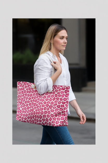 A close-up of a woman carrying the Cheetah Weekender Bag, showcasing its bold pink leopard print and cream rope handles, embodying FireBrook Designs' stylish and adventurous travel ethos.