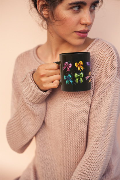 A woman holds a Bows Ribbons Mug (11oz, 15oz) featuring satin ribbons design, showcasing its glossy black ceramic and C-shaped easy-grip handle, ideal for daily use and special occasions.